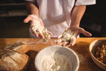 Mid-section of baker mixing flour by hand
