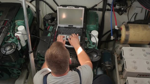Repairer performs diagnostics of the yacht engine
