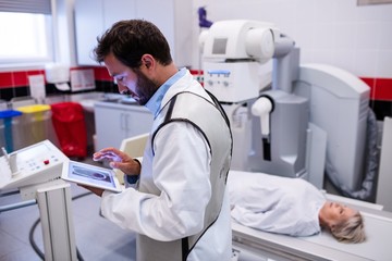 Doctor using digital tablet and patient lying on x ray machine