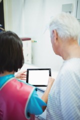 Fototapeta premium Female doctor discussing with patient over digital tablet