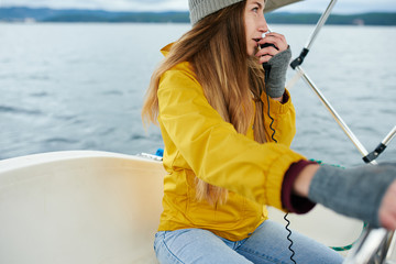 Young woman talking on the radio on the sailboat