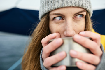 Young woman with thermos warming up in cold weather