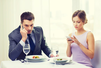busy couple with smartphones at restaurant