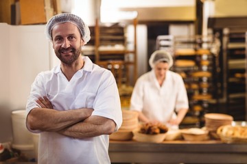 Portrait of male baker standing with arms crossed - obrazy, fototapety, plakaty