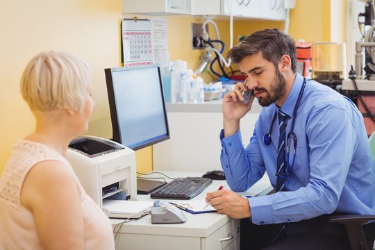 Doctor sitting at his desk and talking on phone