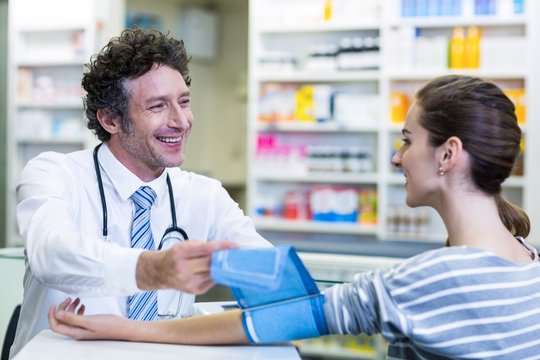 Pharmacist checking blood pressure of customer