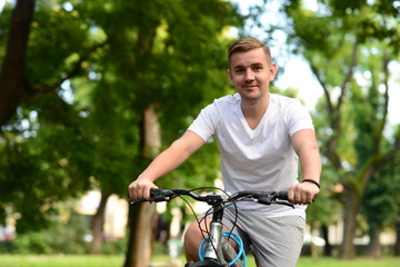 Obraz premium Blonde attractive young man cycling in the park 
