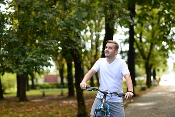 Blonde attractive young man cycling in the park 