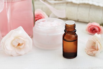 Fototapeta na wymiar eminine spa skincare products, rose scent. Essential oil, jar of body care cream, pink tonic, fresh flowers. Botanical daily skincare regime. 