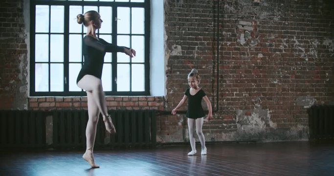 adult ballerina teacher coached a little girl in dance class