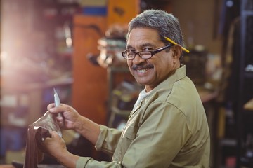 Portrait of smiling shoemaker cutting a piece of leather - Powered by Adobe