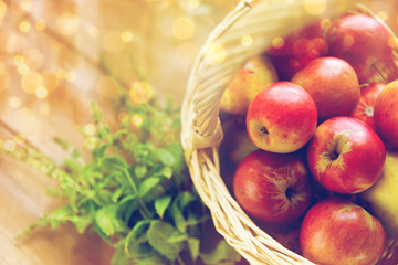 close up of basket with apples and herbs on table