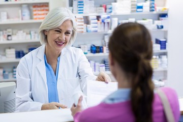 Pharmacist giving prescriptions of medicine to customer - obrazy, fototapety, plakaty