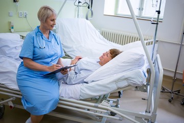 Nurse writing on clipboard while interacting with a patient