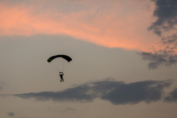 Silhouette of parachute and airplane on sunset background