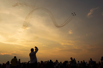 People taking pictures on a airshow at sunset