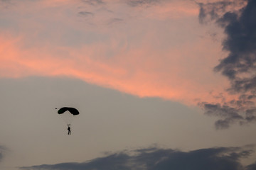 Silhouette of parachute and airplane on sunset background