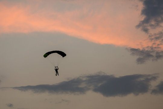 Silhouette of parachute and airplane on sunset background