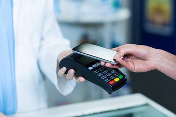 Woman paying bill through smartphone using NFC technology