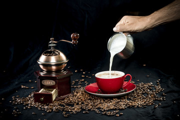 Historische Kaffeemühle, Kaffeebohnen und ein Cappuccino