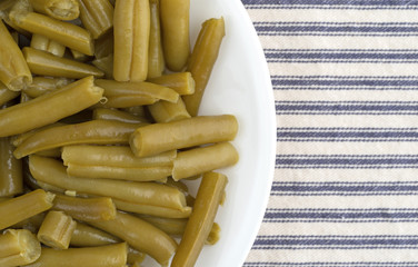 Plate of organic cut green beans on a tablecloth top view.