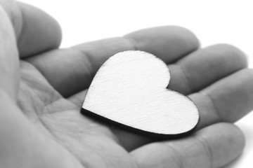 Close up macro man hand holding wooden heart, love symbol on white background, black and white effect with selective focus
