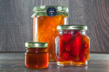Decorated pot with honeycomb dipped in honey, a mini pot with honey and a pot with peppers dipped in honey. 