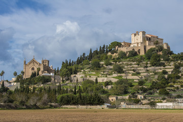 Fototapeta na wymiar SPAIN, ,MAJORCA, ARTA, 2015-02-02: The churches Transfiguració del Senyor and San Salvador on the hilltop, surrounded by the walls of the fortress, dominate the scenery