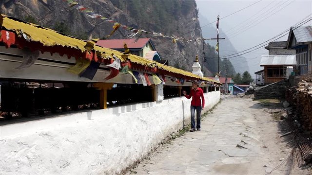 Religion in Asia. Woman spins prayer wheels in Nepal on trek around Annapurna