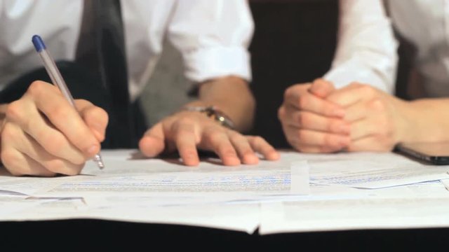 Businessman signs a document at work