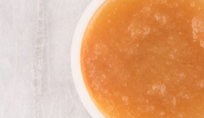 Cinnamon applesauce in a plastic container on a marble table top view.