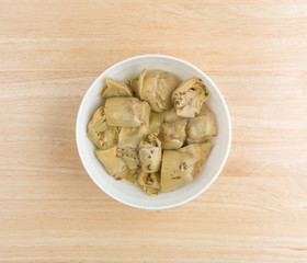Marinated artichoke hearts in a bowl atop a table top view.