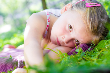 Cute little girl laying in the grass on a sunny summer day © Smailhodzic