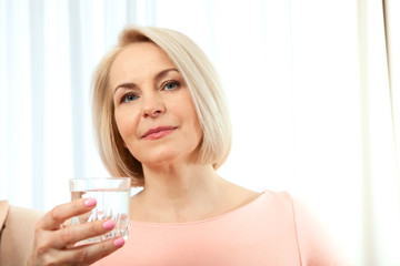 Portrait beautiful middle aged woman drinking water in the morning. Woman's face close up
