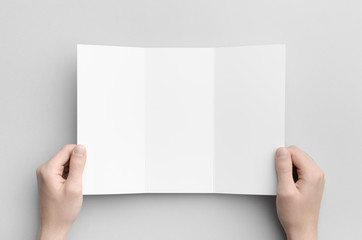 A4 Tri-Fold Brochure Mock-Up - Male hands holding a blank tri-fold on a gray background.