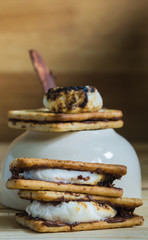 Smores and burnt marshmallow on wooden table, pan as background