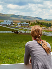 Woman girl leaning on fence of horse paddock ranch