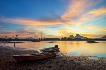 Fototapeta na wymiar Beautiful majectic sunrise by the lakeside with fishing boats. Nature landscape.