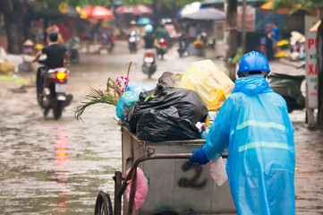 Trash Collector working on community street in raincoat - Hanoi, Vietnam