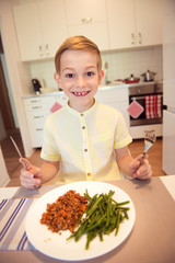 Young diligent happy boy  at a table eating healthy meal with cu