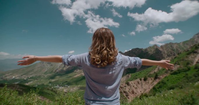 Successful woman raising hands on the top of mountain