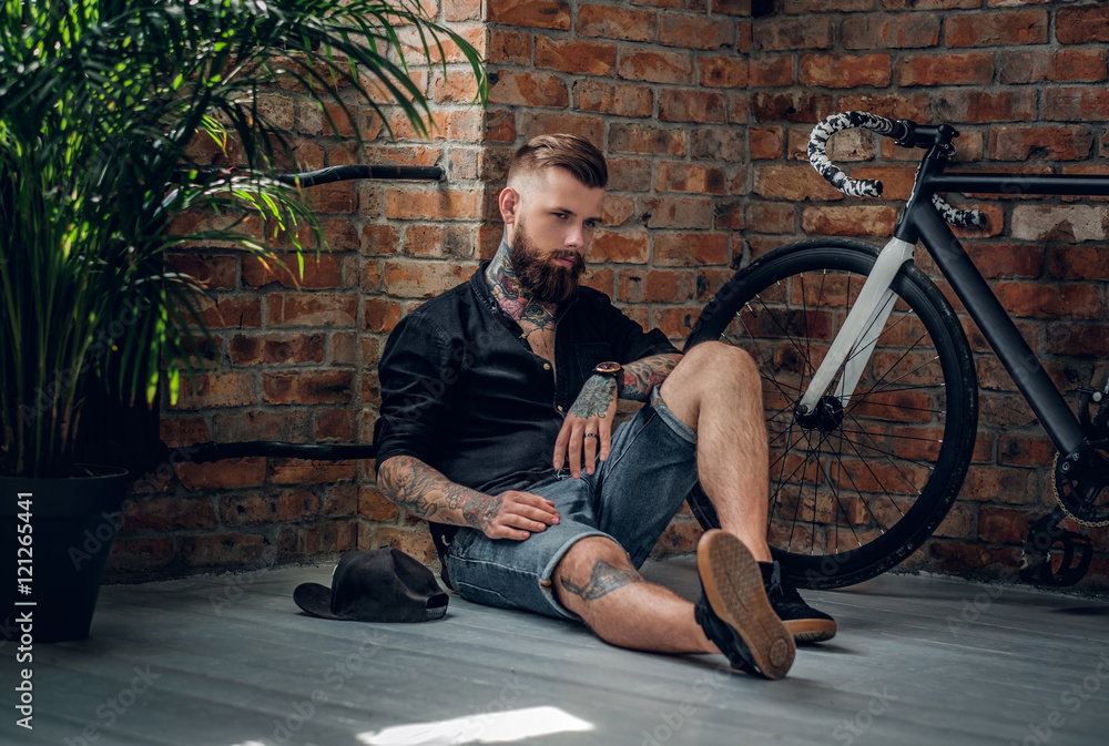 Sticker Tattooed hipster male in a room with bicycle on background.