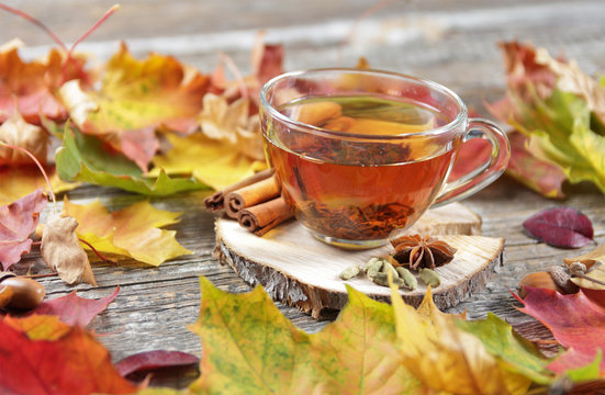 cup of tea on the wooden background with autumn leaves