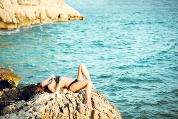 Fototapeta na wymiar Bikini girl posing on sea rocks