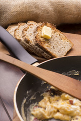 scrambled eggs with bacon in a frying pan to toast and tea
