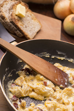 scrambled eggs with bacon in a frying pan to toast and tea