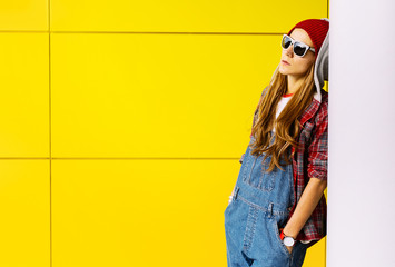Stylish Brunette standing at the yellow wall. Autumn fashion sty