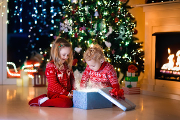 Kids opening Christmas presents at fireplace