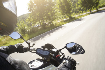 Motorradfahrer fährt auf Straße im Sommer