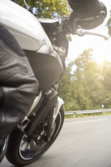 Fototapeta premium Motorradfahrer fährt auf Straße im Sommer